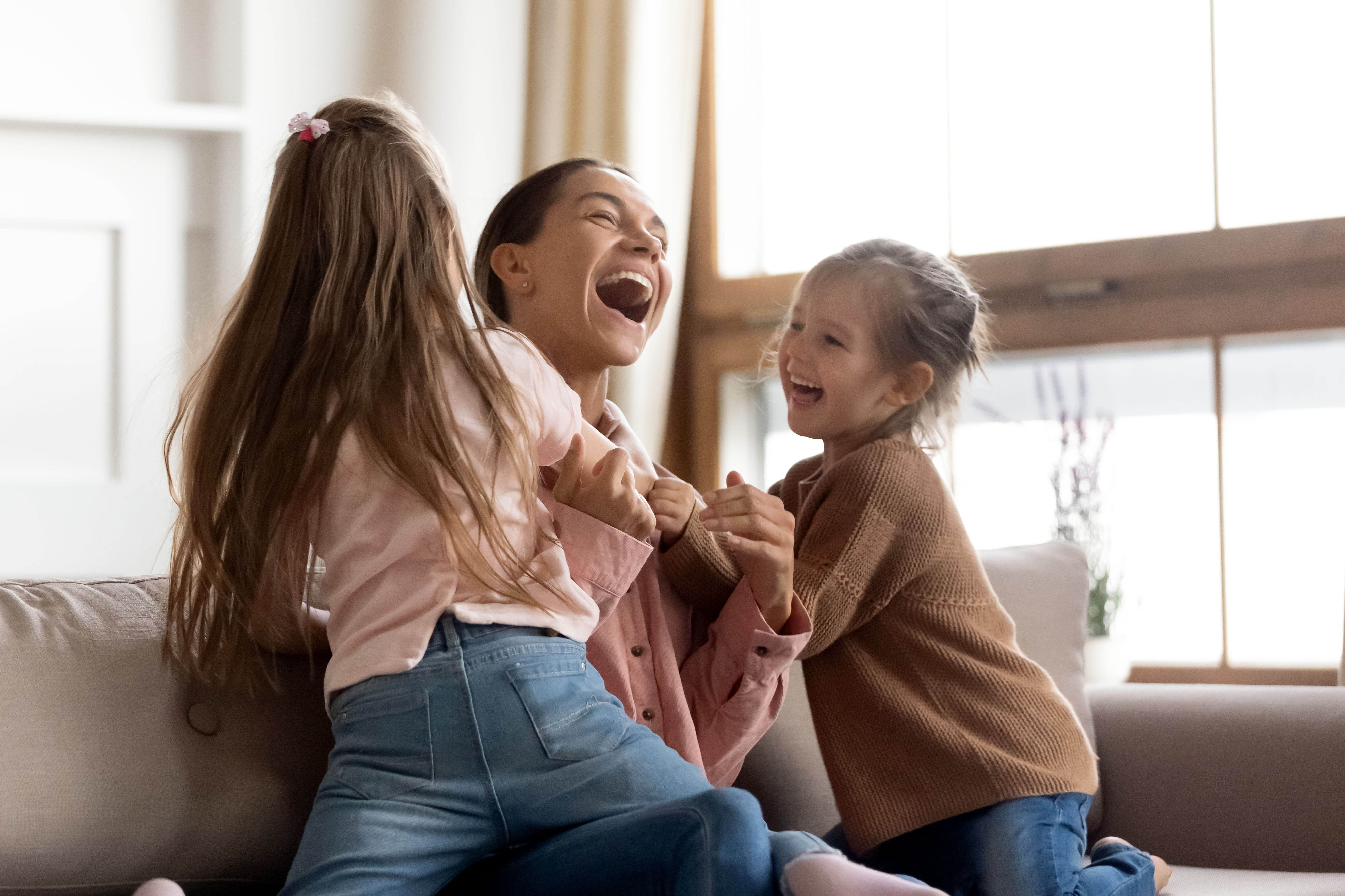 Two children laughing and playing with their mother