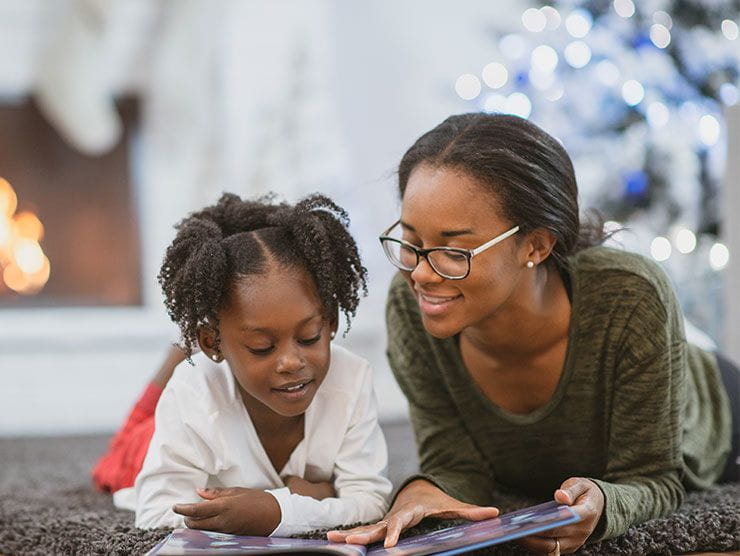 Mother and daughter reading on a carpet.
