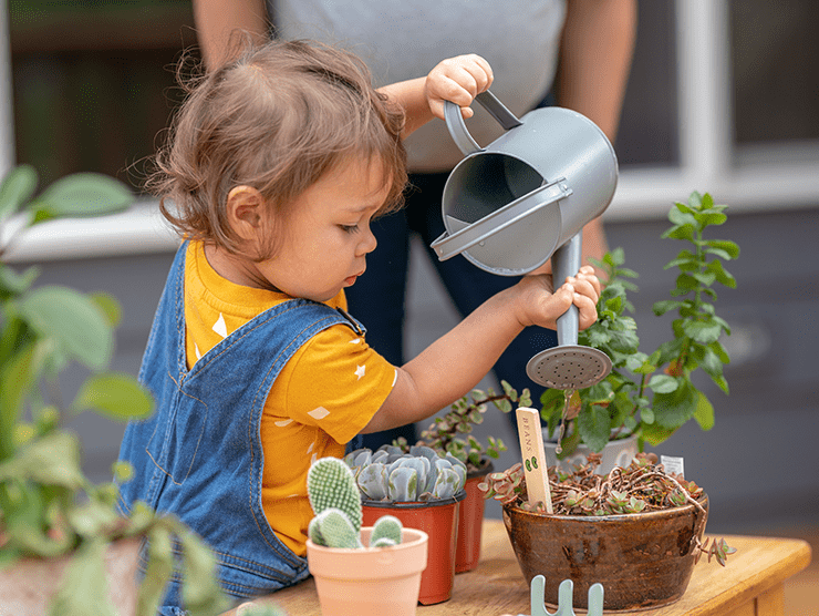 Small child watering a flower pot