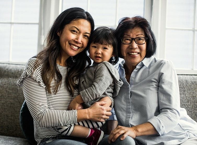 Mother, daughter, and grandmother sitting together on the couch