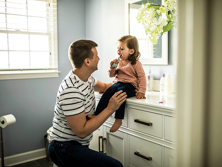 Father helping his daughter brush her teeth