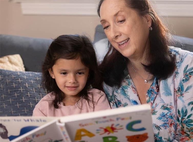 Mother and daughter reading a picture book on the couch
