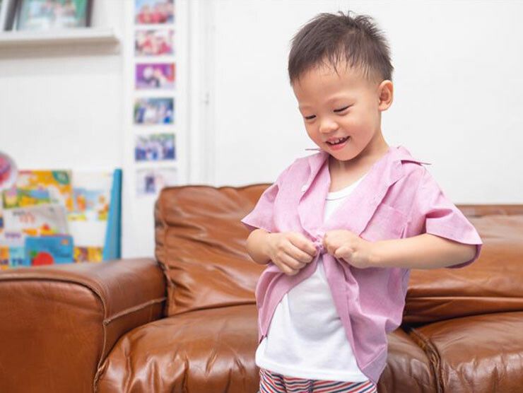 Young boy getting dressed for school