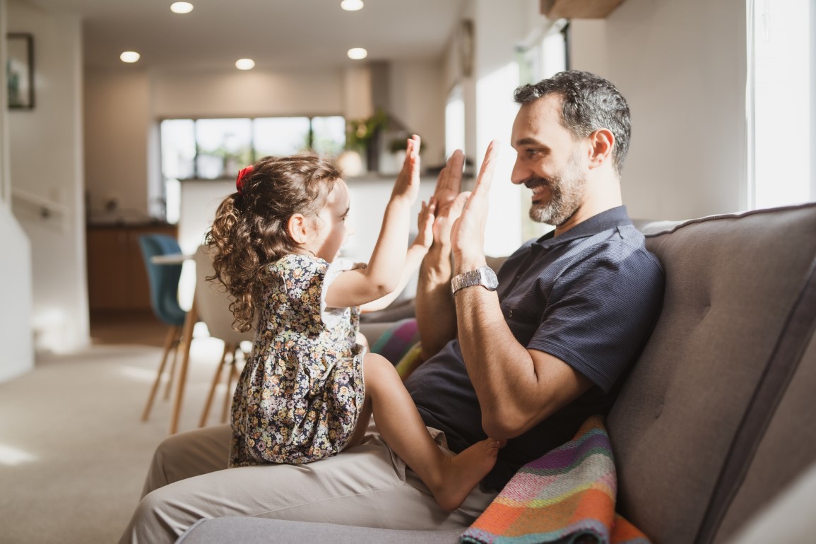 Man and daughter playing on couch