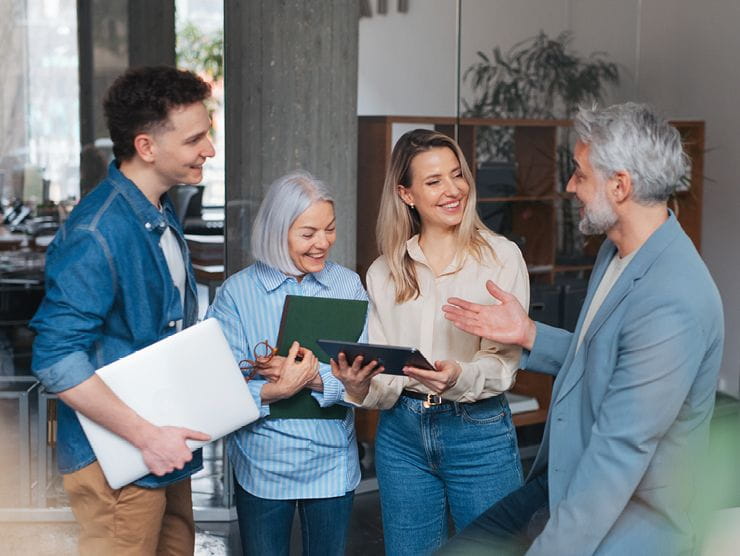 Four working professionals talking to each other in an office setting.