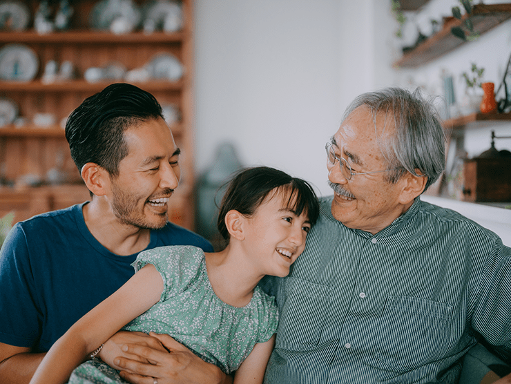 An elderly man sitting with his son and granddaughter