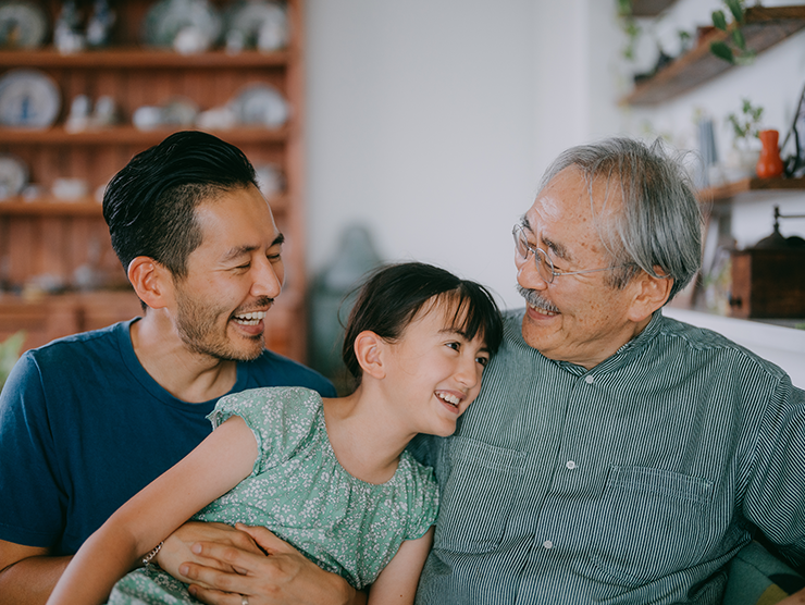 An elderly man sitting with his son and granddaughter