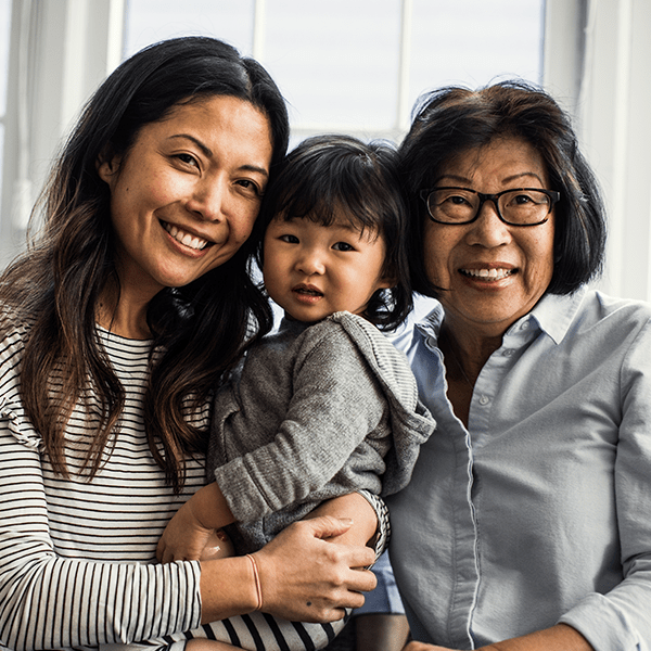 A mother, daughter, and grandmother smiling. 