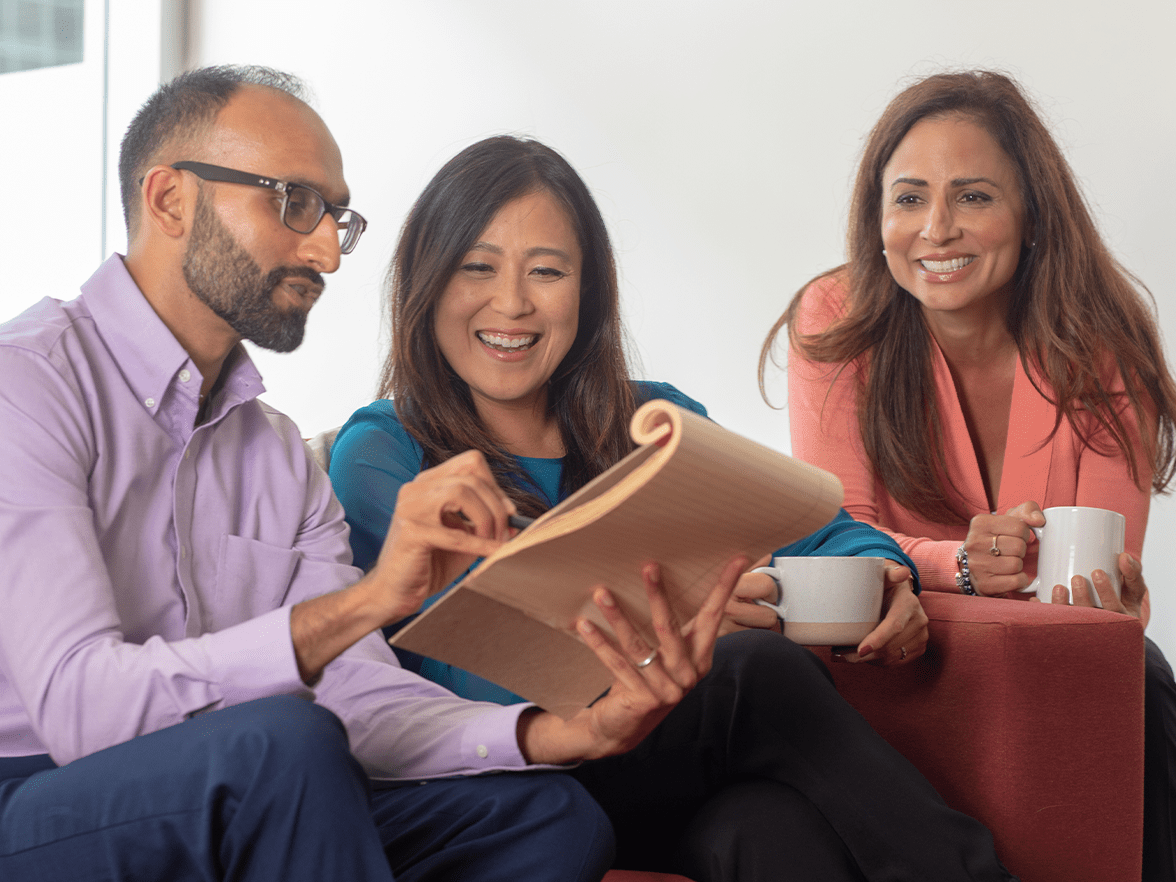 Three professionals reviewing a notepad. 