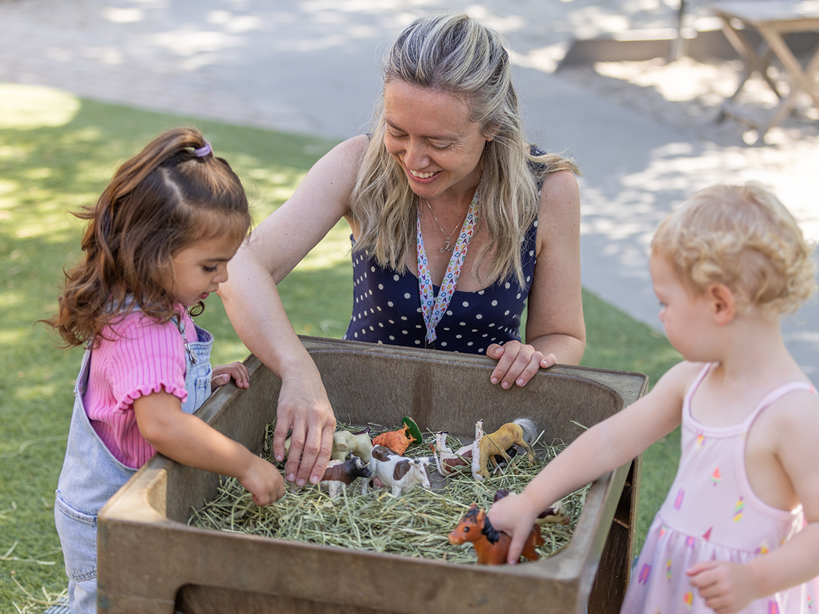 A woman and two school-aged girls playing outside. 
