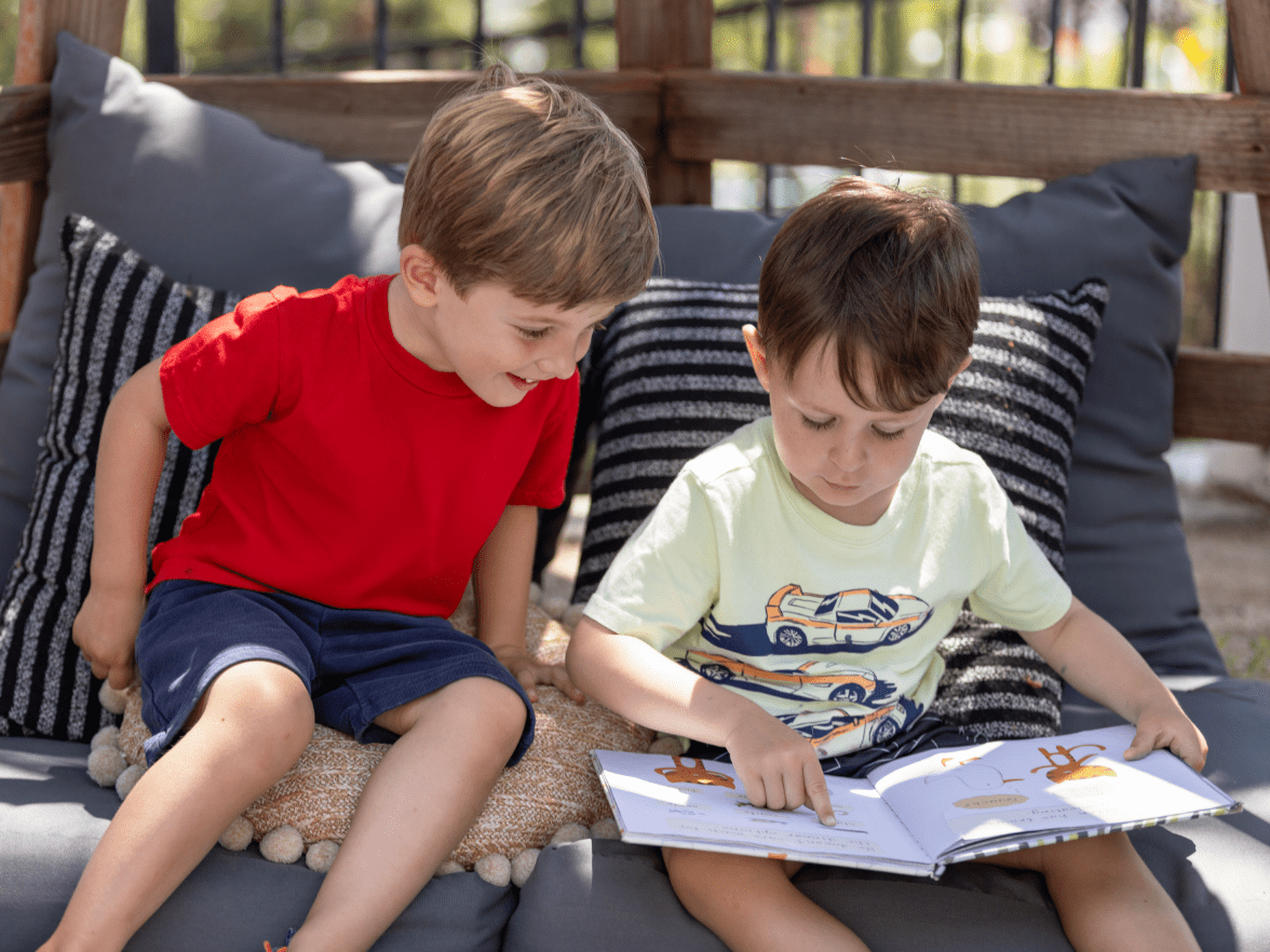 Kindergarten children reading a picture book together in an outdoor classroom space, building early literacy skills in a structured learning environment