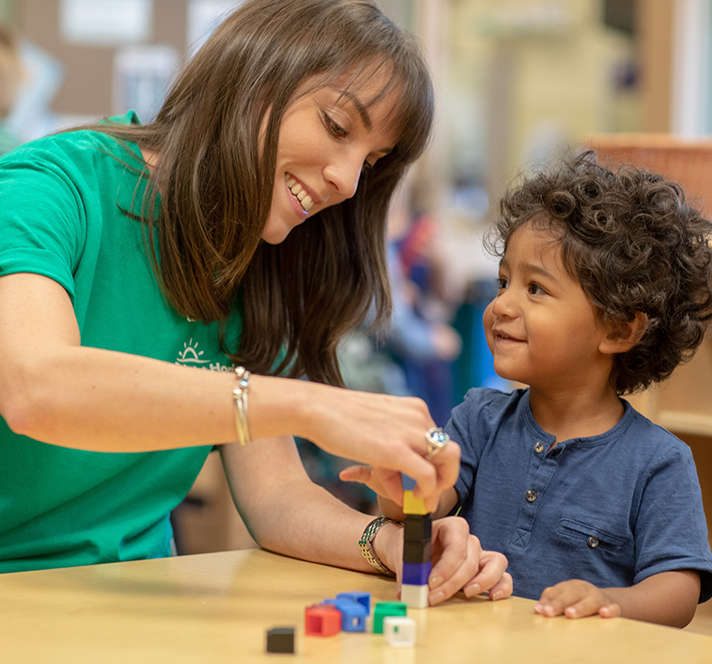 A teacher building blocks with a young boy. 