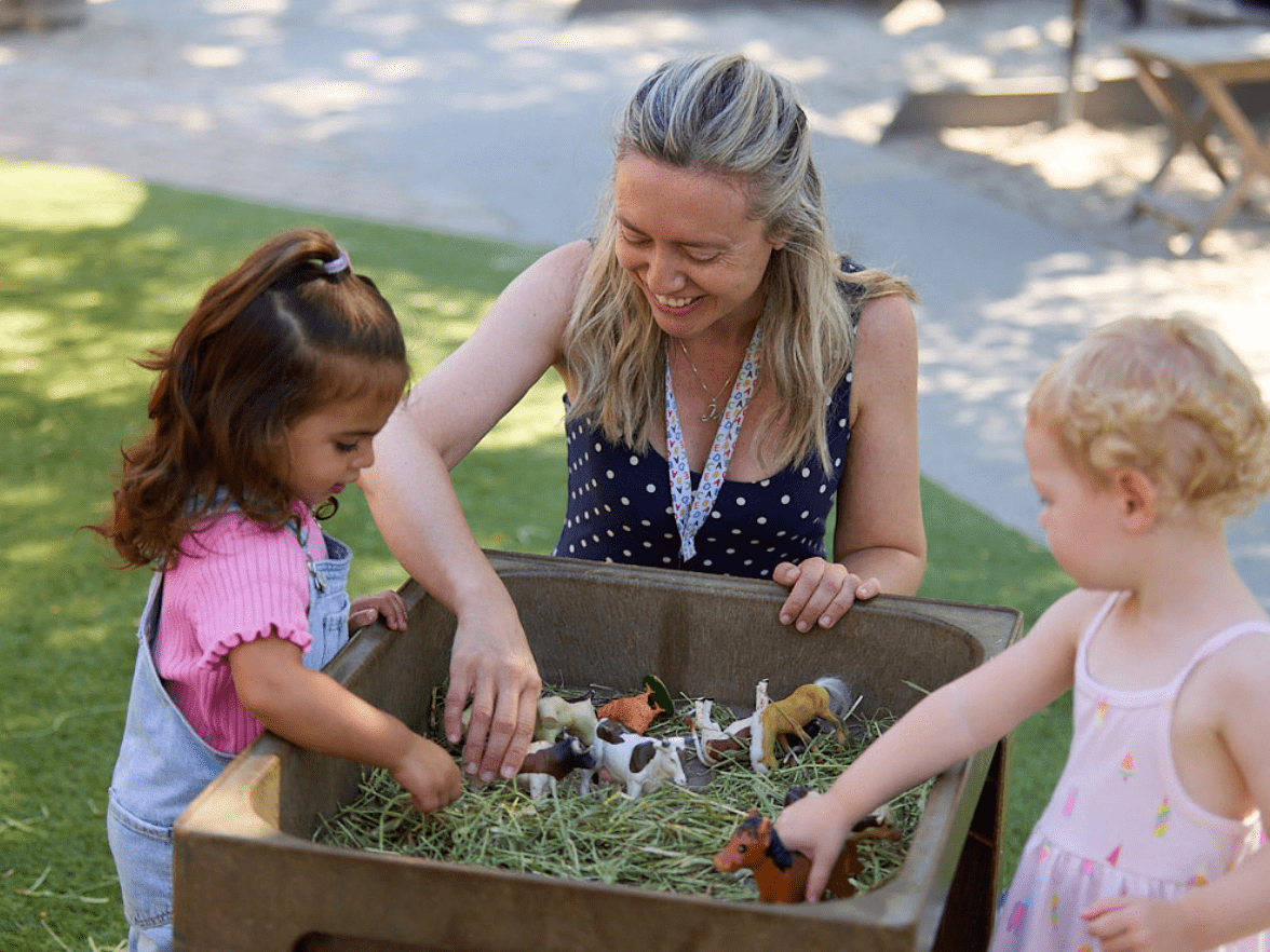Preschool teacher guiding children through hands-on sensory play activity that supports exploration and early learning 