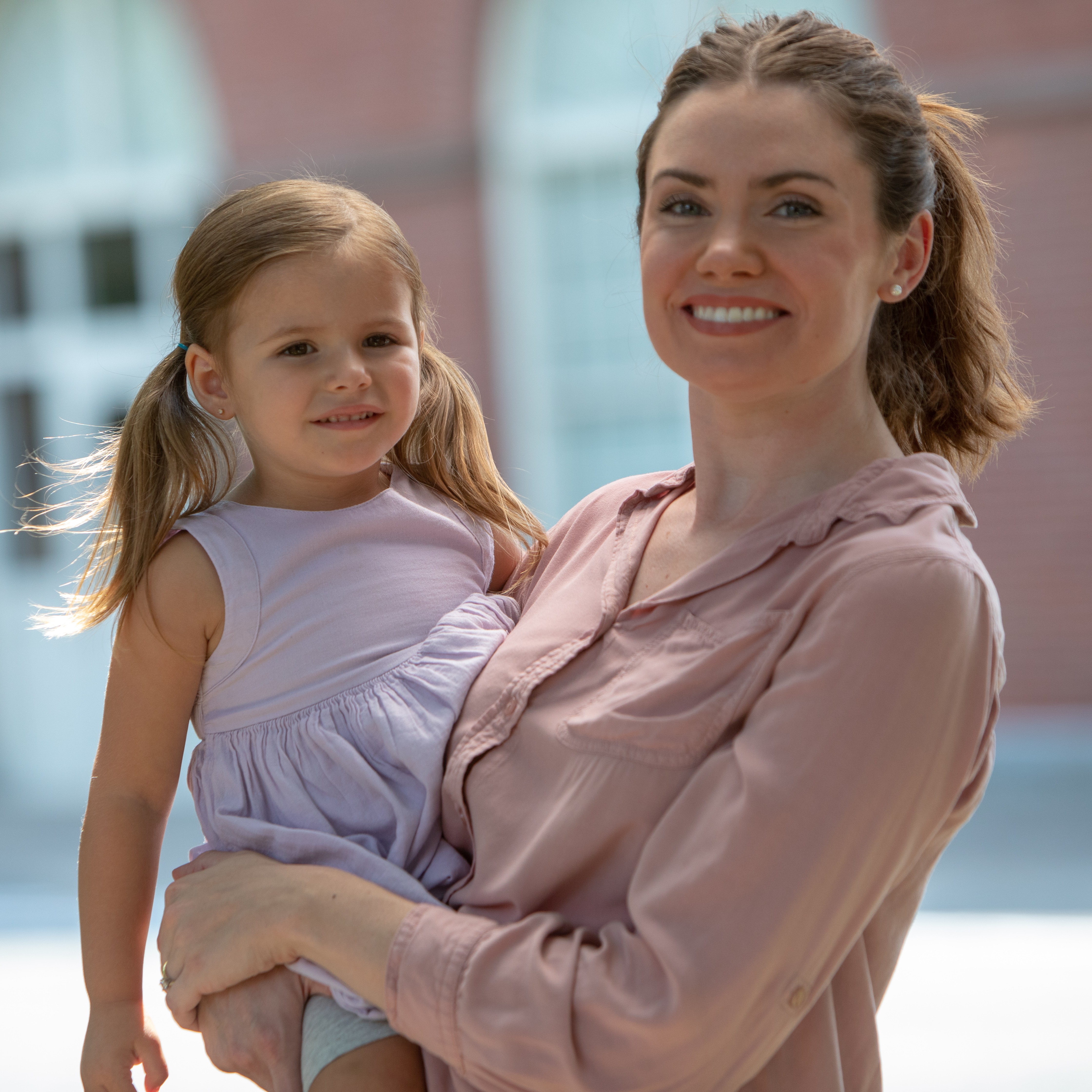 A mother holds her daughter outside. 