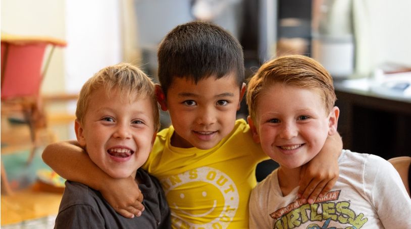 Three toddler boys smiling and hugging