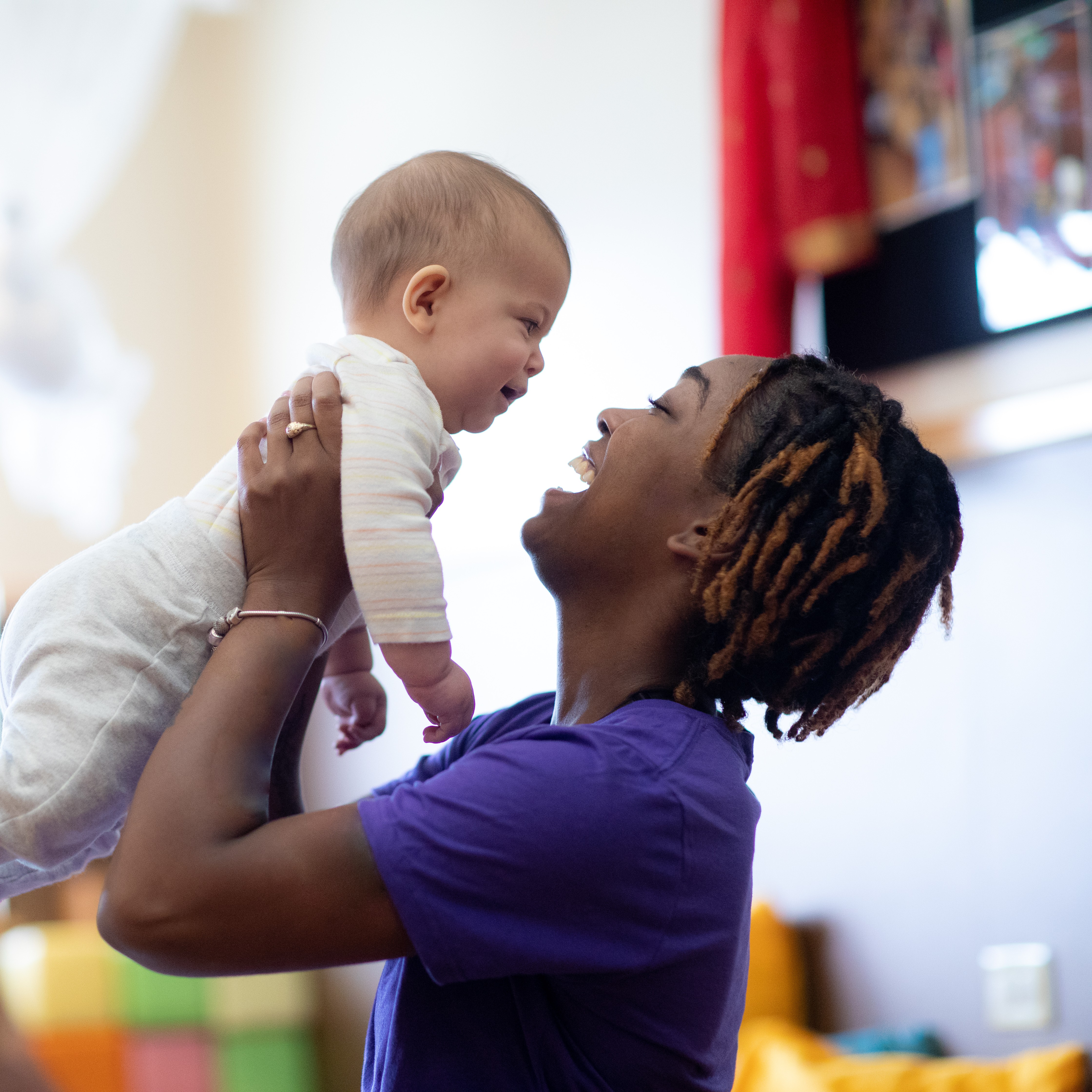 A teacher holds an infant. 