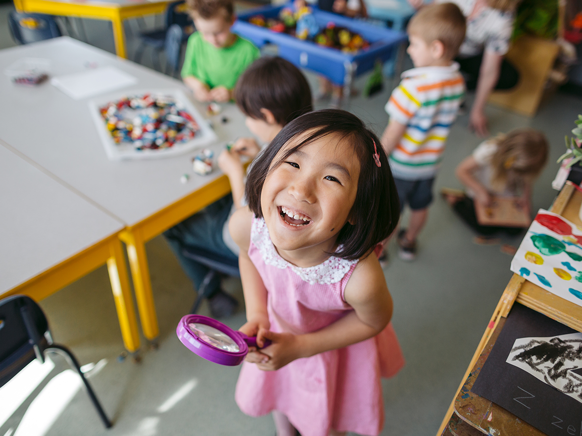 A young girl smiles at toddler preschool. 