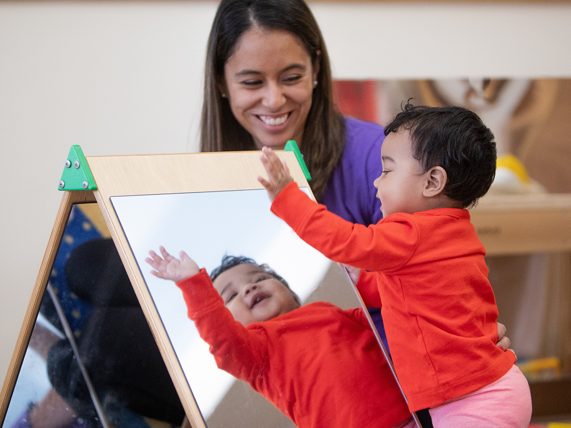 A teacher plays with a toddler at preschool. 