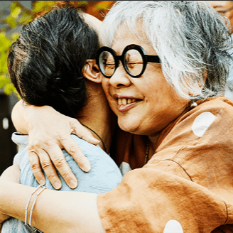 An elderly woman hugging a man. 