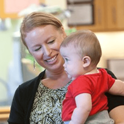 A woman in a Bright Horizons daycare center holding a child