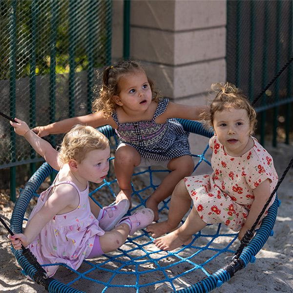 Three young girls playing on a swing
