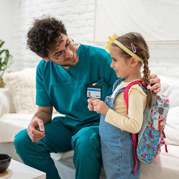 Healthcare professional talking to his young school-aged daughter