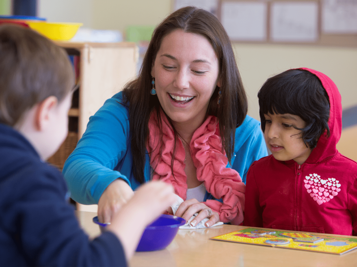 A teacher playing with kindergarten students in a classroom