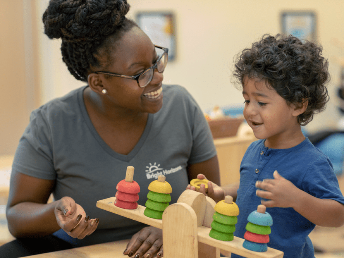 A teacher and toddler playing a game in a classroom