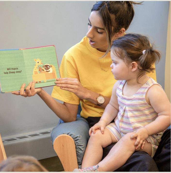 Teacher reading a book to a little girl