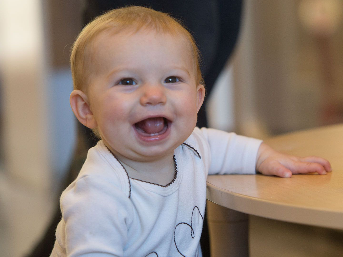 Baby smiling next to a table