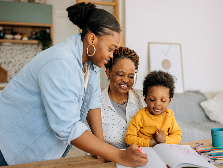 Three generations sitting at the table drawing in a notebook