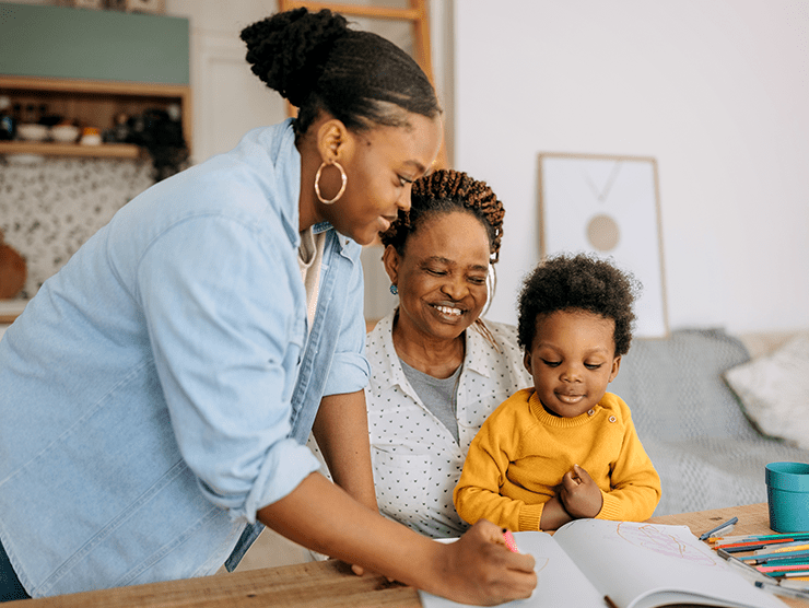 Three generations sitting at the table drawing in a notebook