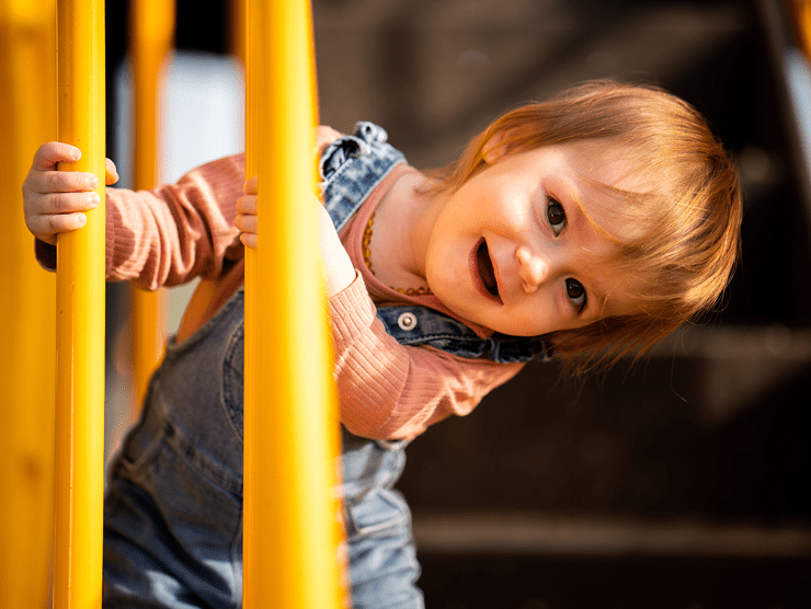 Young child playing on playground equipment at an employer-sponsored child care center