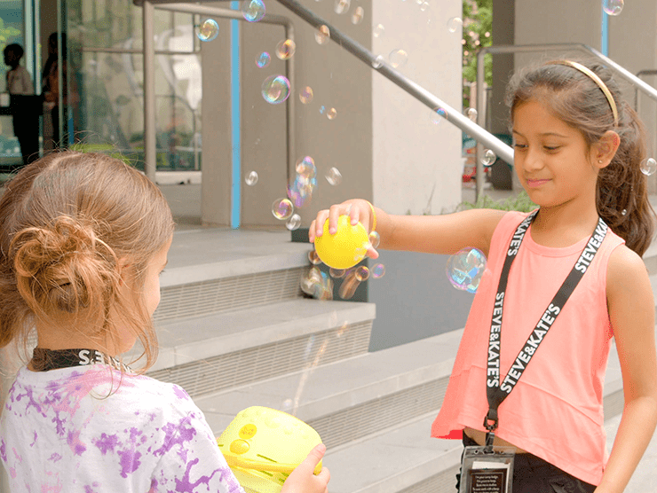 Children playing with bubbles at an employer-sponsored summer camp 