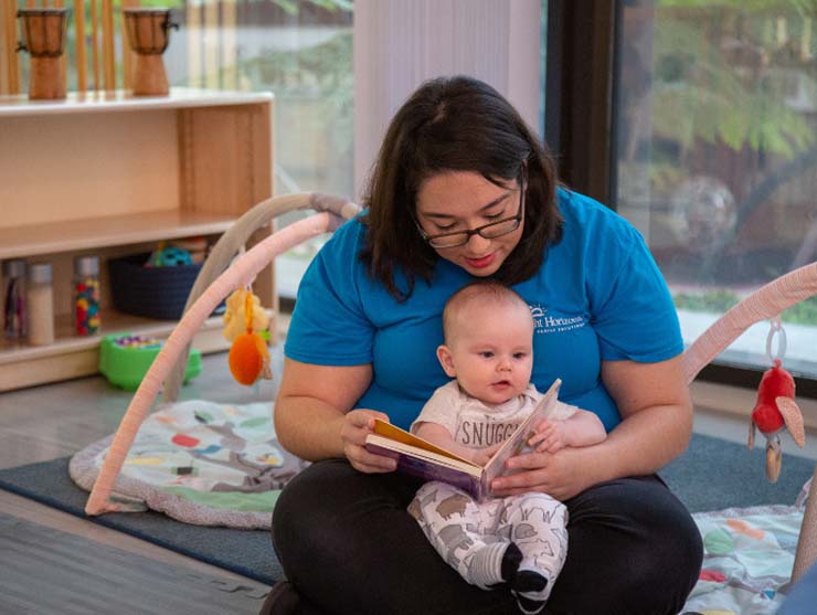 daycare teacher reading a book to a baby