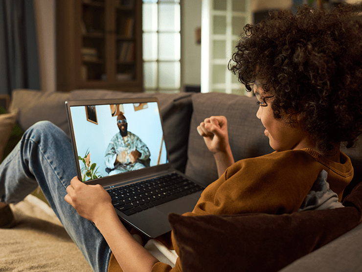 A child talking to a deployed parent through video call in the living room. 