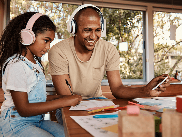 Father and daughter wearing headphones, watching a video on phone. 