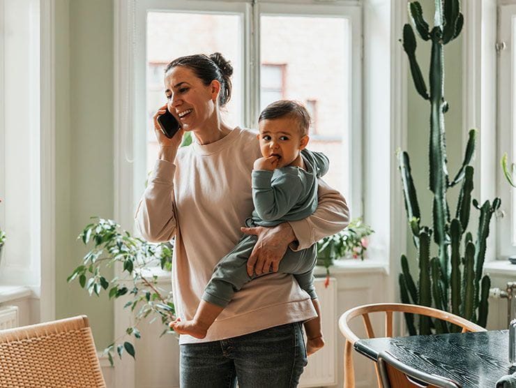 A woman holding a baby while on the phone. 