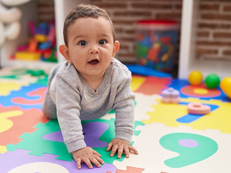 A baby crawling on the floor in a daycare classroom