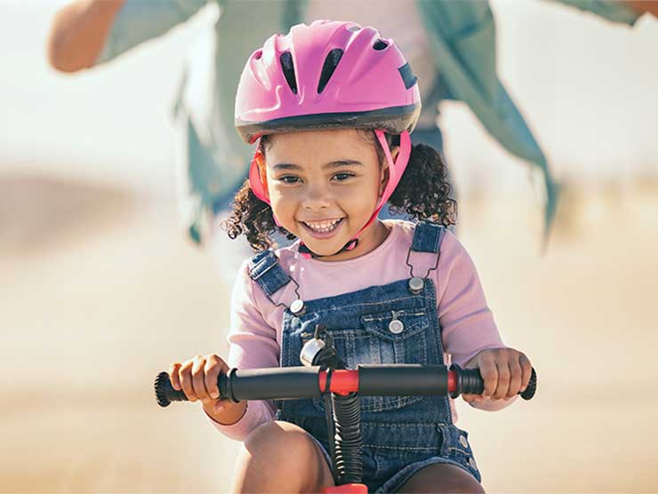 A young girl with a helmet on, riding a bike