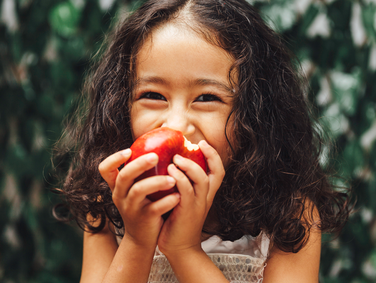 A young girl biting into an apple