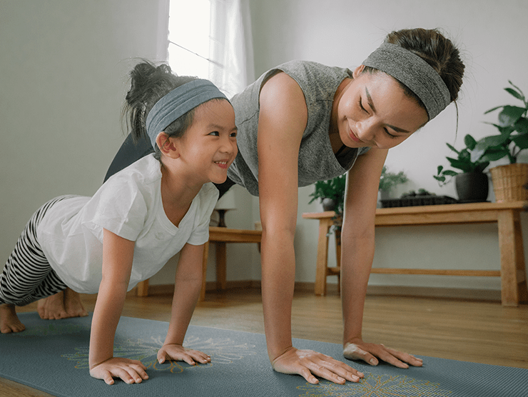 A woman and young child exercising together in a home setting