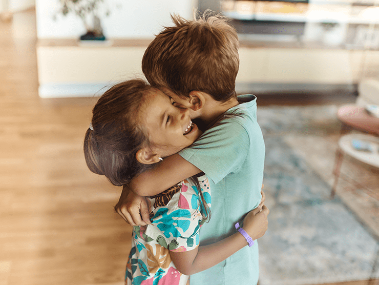Two young children hugging each other at home. 