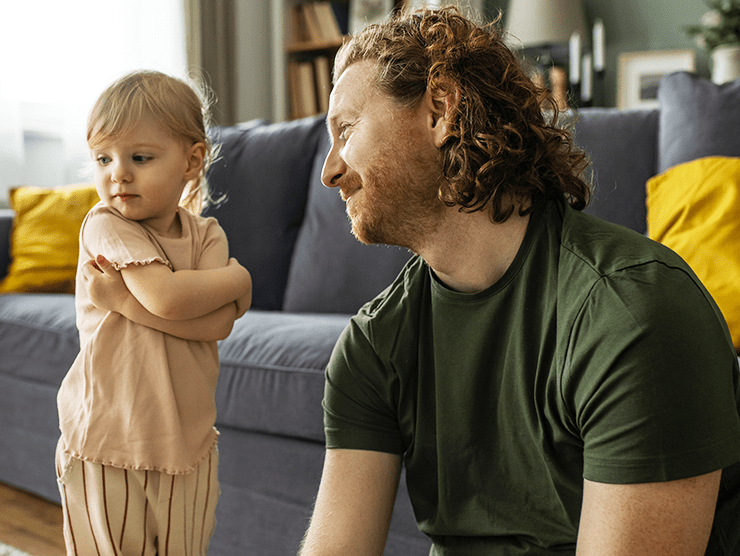 Toddler child crossing their arms and looking away from dad in the living room 