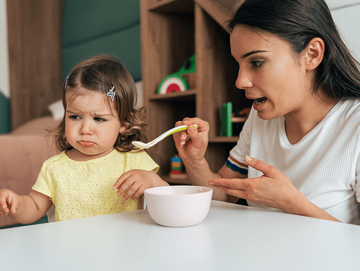 Toddler child turns away from food that caregiver is feeding them