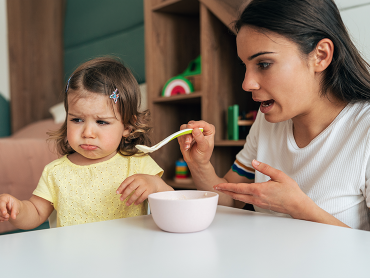 Toddler child turns away from food that caregiver is feeding them
