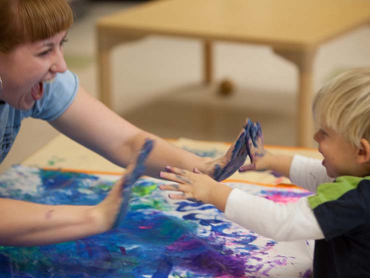 teacher giving a high five to a boy on his first day in a toddler classroom