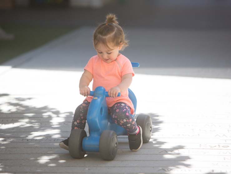 toddler playing outside on a bike