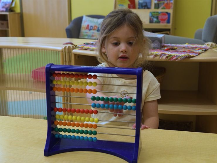 A young girl playing with a toy in a classroom setting