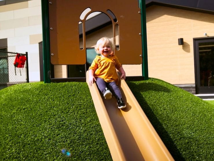 A toddler child sitting on a slide. 